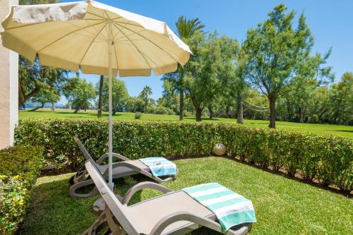 a patio with an umbrella and two lawn chairs and an umbrella at Club del Sol Aparthotel in Port de Pollensa