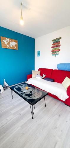 - une chambre avec un canapé rouge et un mur bleu dans l'établissement Le bord 2 mer - Draps et ménage inclus, au Barcarès