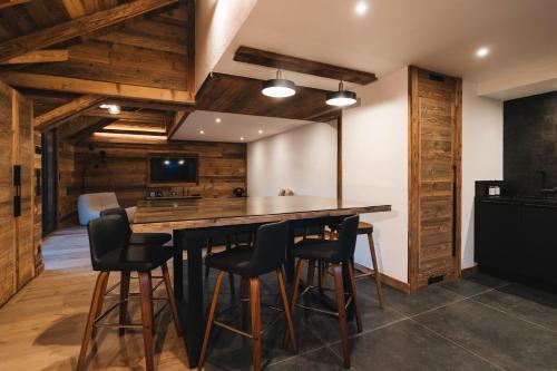 - une cuisine avec une grande table en bois et des tabourets dans l'établissement Gîte Maria, à La Tour