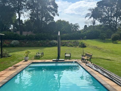 a swimming pool with two chairs and a fountain at Cedara Way Hilton in Hilton