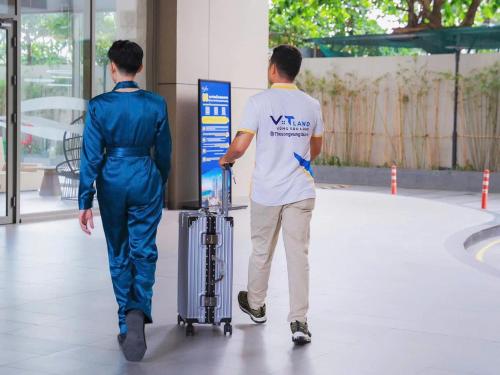 two people walking down a sidewalk with a man with a suitcase at The Song Vung Tau Homestay - VTLand in Vung Tau