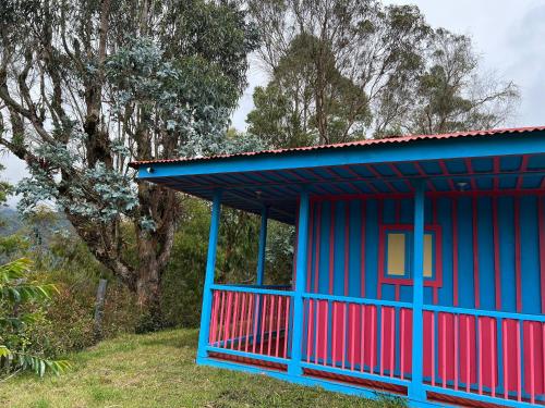 a blue and red building with trees in the background at El Agrado Restaurante Cabañas in Líbano