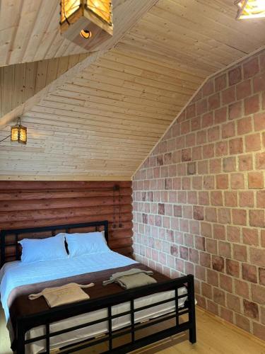 a bed in a room with a brick wall at Davitiani in Tʼelavi