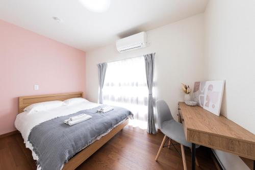 a bedroom with a bed and a desk and a window at Kosumosu in Tokyo