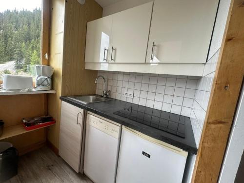 une cuisine avec des armoires blanches, un évier et une fenêtre dans l'établissement Studio divisible rénové, pied des pistes, balcon, 4 pers., La Plagne - FR-1-181-1104, à Plagne Bellecôte