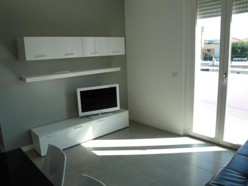 a white living room with a tv on a stand at Residence La Nave in Senigallia