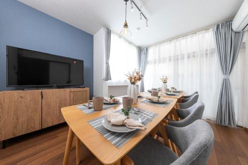 a dining room with a table with chairs and a television at Kosumosu in Tokyo