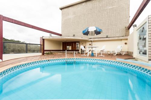 a swimming pool with a table and umbrella on a building at Hotel Lopes Caxambu in Caxambu