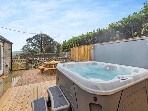 a hot tub sitting on a patio with a table at Heathcote Hideaway - Uk36659 in Hartington