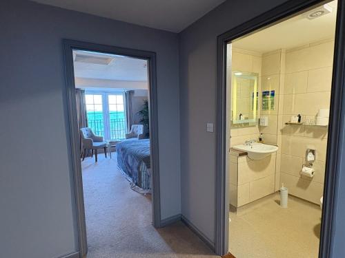 a bedroom with a bed and a bathroom with a sink at The White House Hotel in Herm
