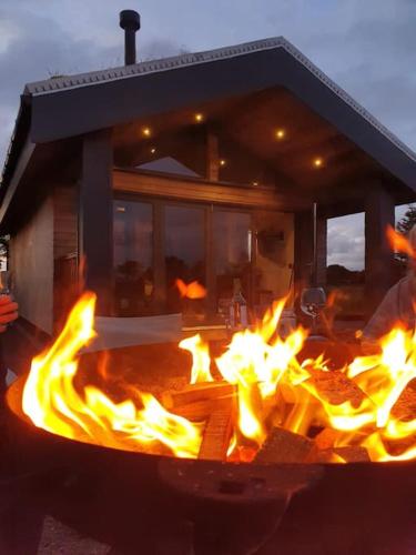 a large fire pit with flames in front of a house at Wildflower Eco Lodges in Fraserburgh