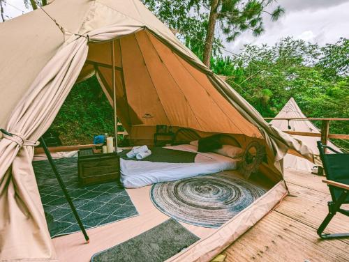 a bed in a tent on a deck at Zenda Glamping in Bao Loc