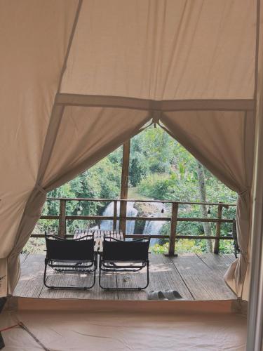 a tent with two chairs on a wooden deck at Zenda Glamping in Bao Loc