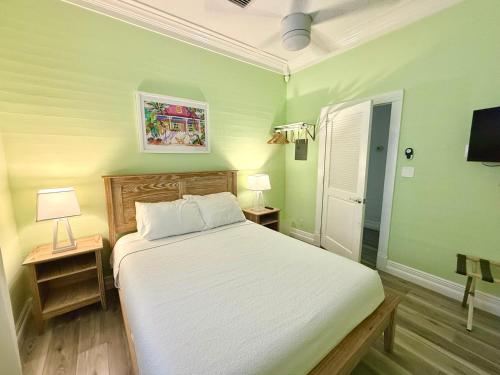 een slaapkamer met een wit bed en twee nachtkastjes bij Atocha Cottage - Harbor Walk Hideaways in Key West