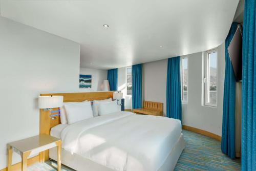 una camera da letto con un grande letto bianco e tende blu di Radisson Blu Hotel, Muscat a Mascate