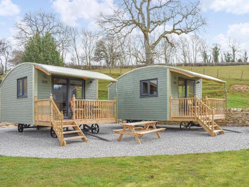 a green tiny house with a picnic table and benches at The Ash Uk38291 in Crosby Garrett