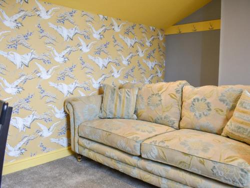 a couch in front of a wall with a wallpaper withorses at Doddick Beck - Uk39153 in Threlkeld