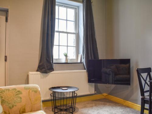 a living room with a tv and a chair and a window at Doddick Beck - Uk39153 in Threlkeld