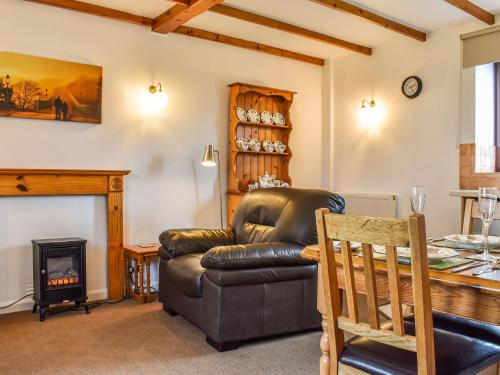 a living room with a leather couch and a fireplace at May Cottage-Uk38279 in Cloughton