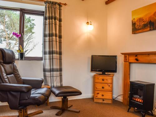 a living room with a chair and a television at May Cottage-Uk38279 in Cloughton