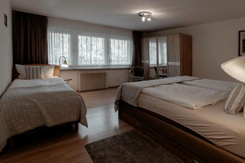 a bedroom with two beds and a desk and window at Waldhotel Rennsteighöhe in Frauenwald