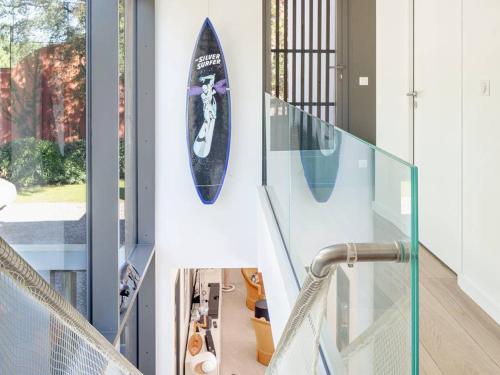 une planche de surf suspendue sur un mur à côté d'un escalier dans l'établissement Villa d'exception avec piscine chauffée, proche plages et commodités - FR-1-791-22, à Soorts-Hossegor