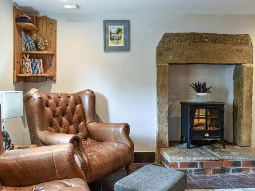 a living room with a leather chair and a fireplace at Johnsons Cottage - Uk39727 in Taddington