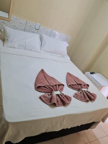 a white bed with two pairs of slippers on it at Hotel Veleiro de Porto in Porto De Galinhas