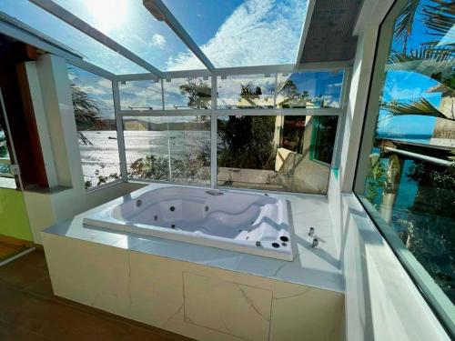 a bath tub in a room with a large window at Pousada Praia da Lagoinha in Bombinhas