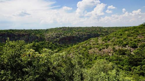 a view of a green hill with trees and clouds at Leopards Rock Bush Boutique in Bela-Bela