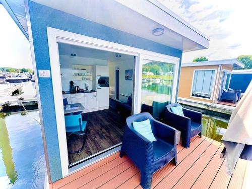 a deck with two chairs and a desk on the water at ''Statia'' Cozy & Romantic Houseboat in Maastricht in Maastricht
