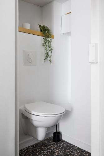 des toilettes blanches dans une salle de bain avec une plante sur le mur dans l'établissement Exlusivité - Cocoon & Erdre - Joli T2 Cosy, à Nantes