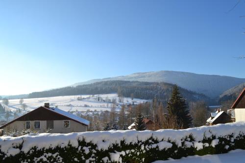 a snow covered hill with a house and a mountain at Ubytování v soukromí - U Hlinků in Horní Maršov