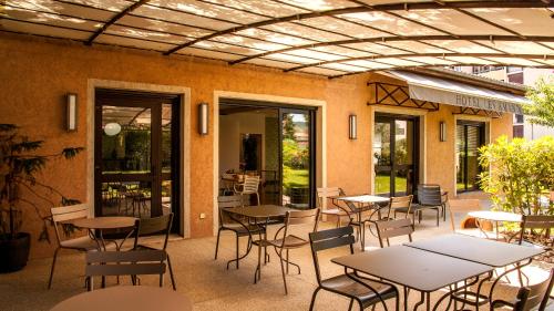 a patio with tables and chairs in a restaurant at Hotel Les Amandiers in Tournon-sur-Rhône