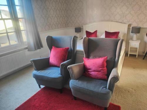 a bedroom with two chairs and a bed with red pillows at The Royal Oak in Bere Regis
