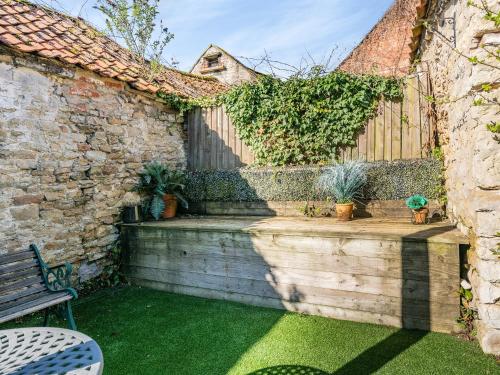 a garden with a bench and a brick wall at Beverley House - Uk43519 in Thornton Dale