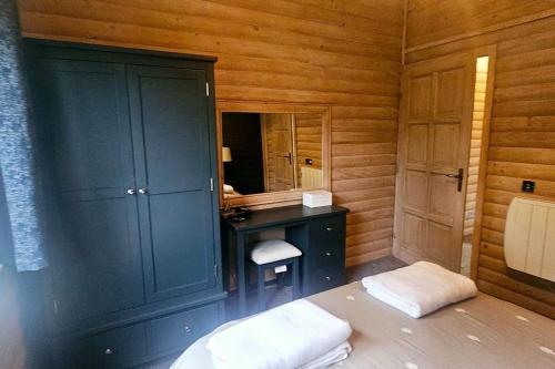 a bathroom with a blue cabinet and a vanity with a mirror at Heather Lodge with Hot Tub in Holcombe Burnell