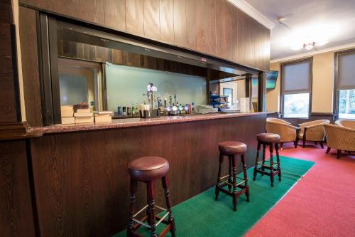 a bar with stools in a room at Rossmore Hotel in Ilford