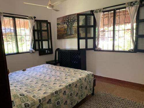 ein Schlafzimmer mit einem Bett in einem Zimmer mit Fenstern in der Unterkunft Hibiscus in Mambrui in Mambrui