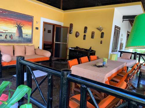 ein Esszimmer mit Tisch und Stühlen und einer Couch in der Unterkunft Hibiscus in Mambrui in Mambrui