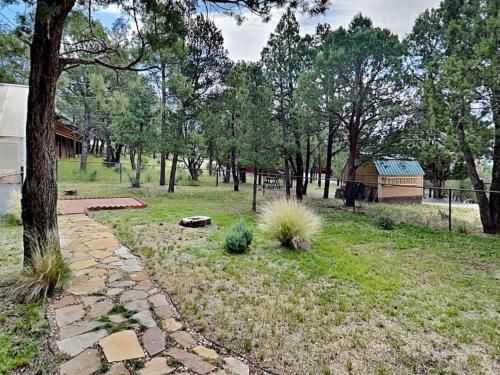 a garden with a stone path and trees and a barn at Tanglewood in Ruidoso