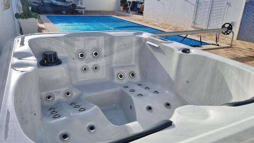 a white bath tub sitting in front of a pool at Villa O Canto da Parra - Hot Jacuzzi - Swimming Pool - WIFI - BY BEDZY in Galé