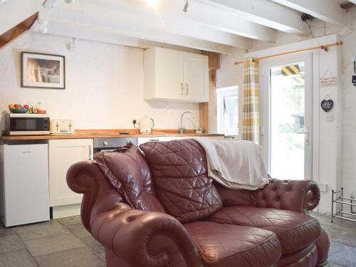 a brown leather couch in a kitchen with a counter at Y Stabl - Uk35032 in Carmarthen