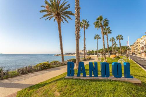 Un cartel azul que dice "Ampa" sentado en el césped cerca del océano. en Hotel de la Baie, en Bandol