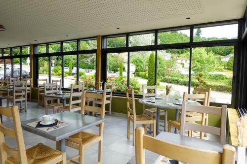 un restaurant avec des tables, des chaises et des fenêtres dans l'établissement Hotel Restaurant de la Poste, à Saint-Just-en-Chevalet
