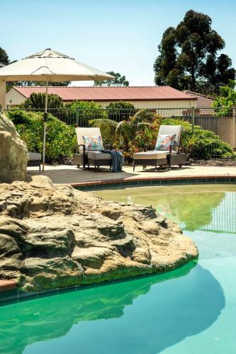 two chairs and an umbrella next to a swimming pool at Carinya Cove - swimming pool, pet friendly, fireplace in Dunsborough