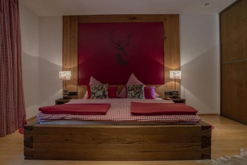a bedroom with a large bed with a red wall at Sportalm Seefeld - Ski In Ski Out Doppelzimmer in Seefeld in Tirol