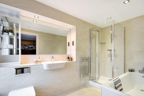 a bathroom with a sink and a tub and a mirror at Comfortable Studio For 2 In Leeds with Free Grab&Go Breakfast in Headingley