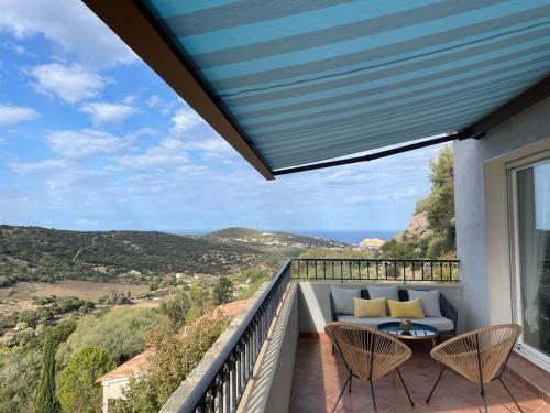 d'un balcon avec vue doté d'un canapé et de chaises. dans l'établissement Superbe villa vue mer avec piscine, à Santa-Reparata-di-Balagna