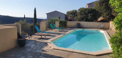 une grande piscine avec des chaises et une maison dans l'établissement Superbe villa vue mer avec piscine, à Santa-Reparata-di-Balagna